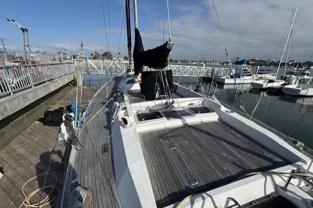 Slide: The Image of 1983 Tayana 55 sailboat docked at marina, wooden deck, clear sky. - 4