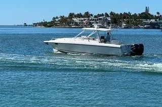 The Image of 2001 Intrepid 377 Walkaround boat cruising on clear blue water near a coastal town. - 0