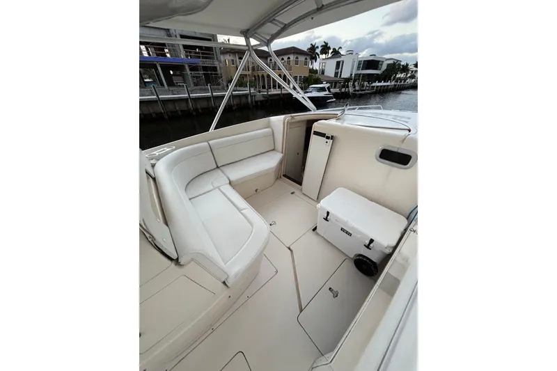 Slide: The Image of 2001 Intrepid 377 Walkaround boat interior with white seating and cooler, dockside view. - 19