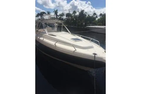 The Image of 2001 Intrepid 377 Walkaround boat docked by palm trees under a cloudy sky. - 2