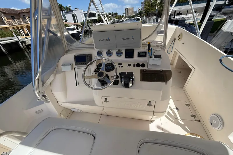 Slide: The Image of 2001 Intrepid 377 Walkaround helm with Garmin navigation, docked by waterfront homes. - 8