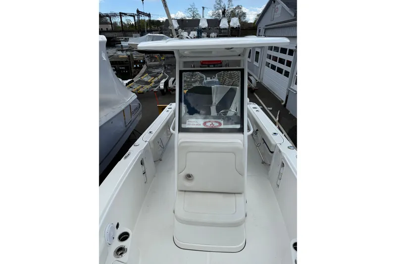 Slide: The Image of 2022 Edgewater 230CC boat, white interior, docked at marina, view of console and seating. - 10