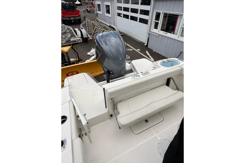 Slide: The Image of Edgewater 230CC 2022 boat with outboard motor and seating, docked near a building. - 12