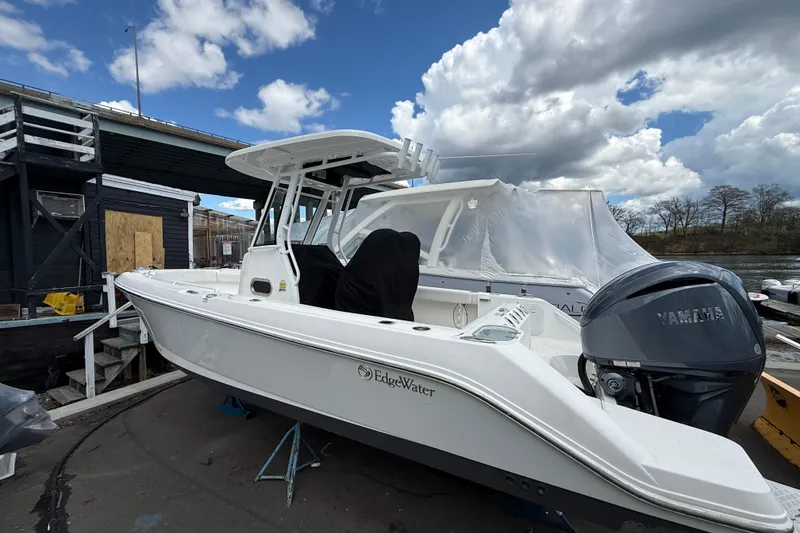 Slide: The Image of 2022 Edgewater 230CC boat with Yamaha engine docked under cloudy sky. - 2