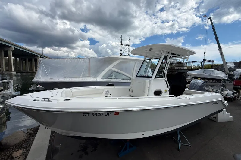 Slide: The Image of 2022 Edgewater 230CC boat docked near a bridge under cloudy skies. - 3