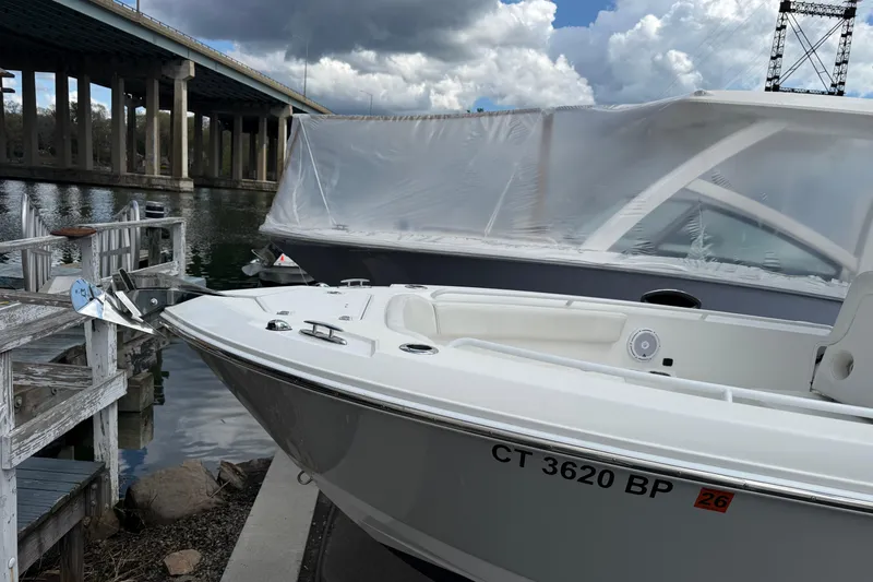 Slide: The Image of 2022 Edgewater 230CC boat docked near a bridge under cloudy skies. - 4