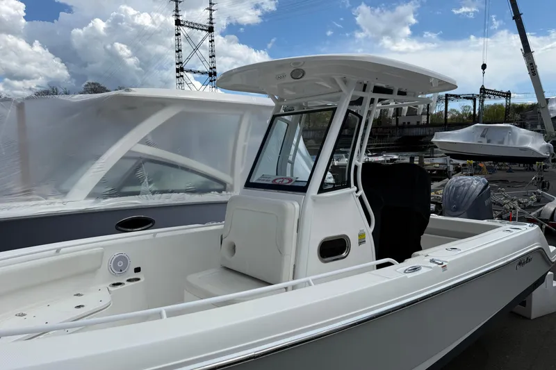 Slide: The Image of 2022 Edgewater 230CC boat with T-top, docked under cloudy sky. - 5