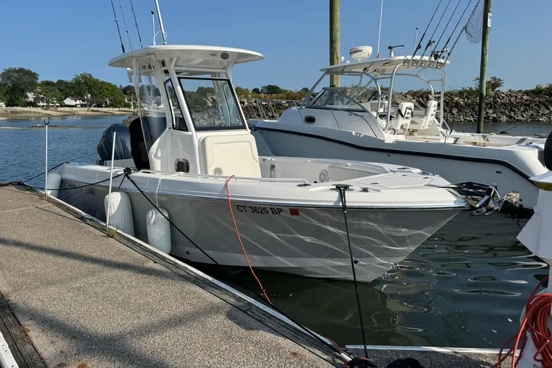 Slide: The Image of 2022 Edgewater 230CC boat docked at marina, clear day, fishing rods visible. - 7