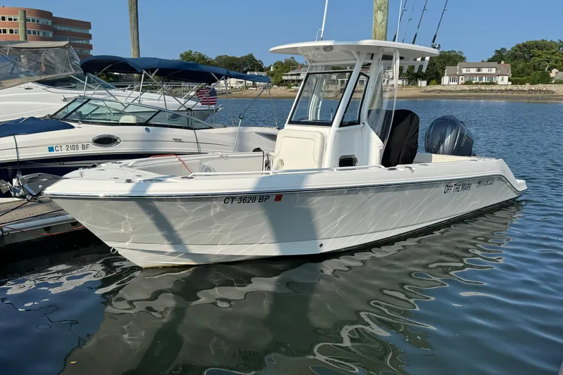 Slide: The Image of 2022 Edgewater 230CC boat docked in a marina, reflecting on calm water. - 8