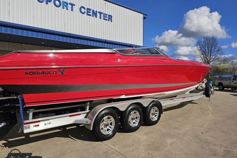 Slide: The Image of Red 1997 Formula 382 FASTech boat on trailer outside a sport center, under blue sky. - 12