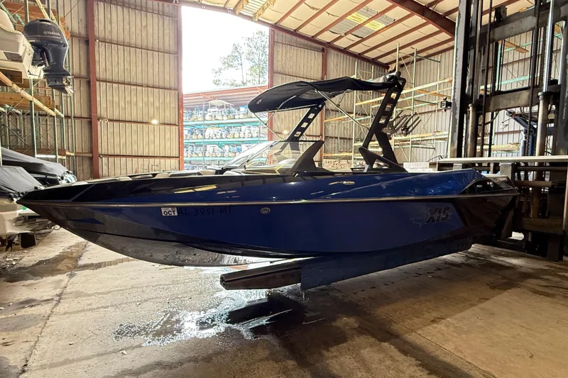 The Image of 2015 Axis T23 boat in storage, blue hull, indoor warehouse setting. - 1