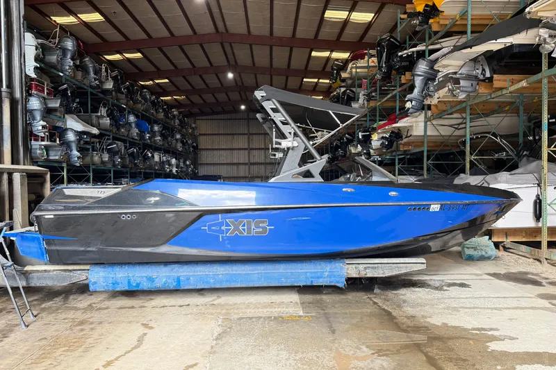Slide: The Image of 2015 Axis T23 boat in storage, blue and black design, surrounded by marine equipment. - 5