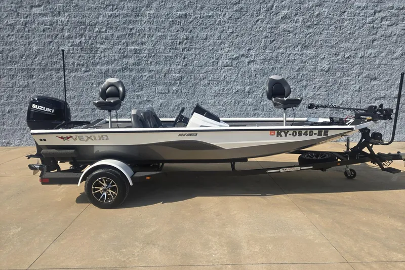 The Image of 2021 Vexus AVX181 boat with Suzuki motor on trailer, parked against a gray wall. - 1