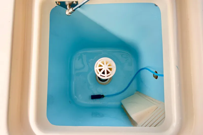 Slide: The Image of Livewell interior of 2022 Grady-White Freedom 235 boat, featuring blue basin and drain. - 10