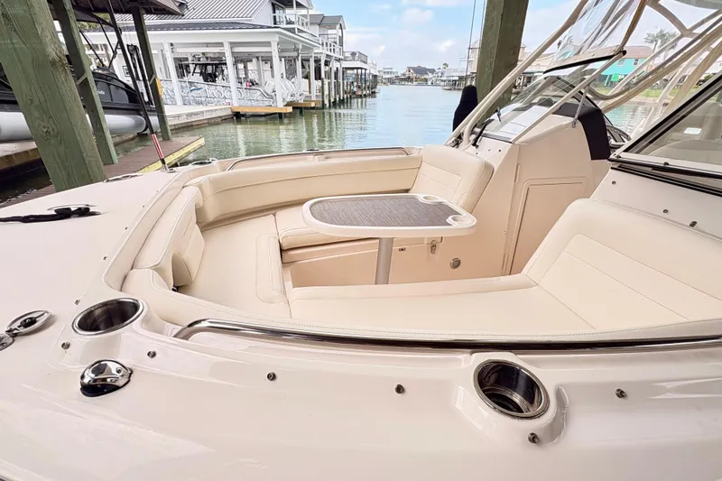 Slide: The Image of 2022 Grady-White Freedom 235 boat interior with seating and table, docked by waterfront homes. - 17