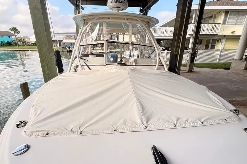 Slide: The Image of 2022 Grady-White Freedom 235 boat docked with cover, featuring Garmin equipment. - 8