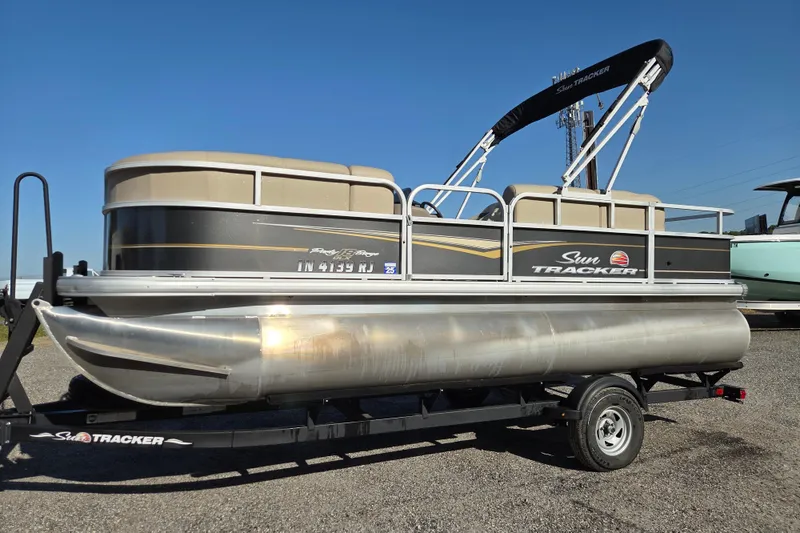The Image of 2022 Sun Tracker Party Barge 18 DLX pontoon boat on trailer, sunny day. - 0