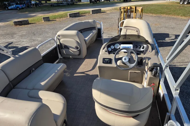 Slide: The Image of 2022 Sun Tracker Party Barge 18 DLX interior with beige seating and steering console. - 10