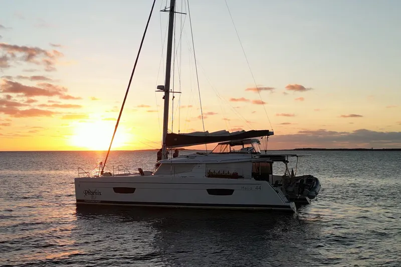 The Image of 2018 Fountaine Pajot Helia 44 Evolution catamaran sailing at sunset on calm waters. - 0