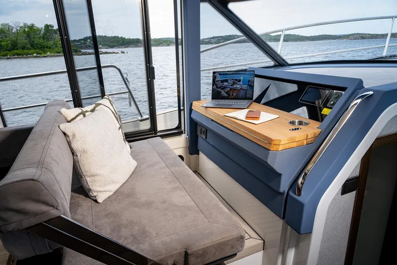Slide: The Image of Manufacturer Provided Image: 2025 Marex 440 Scandinavia yacht interior with sofa, desk, and scenic water view. - 11