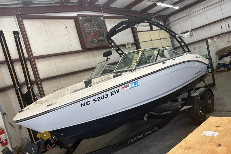 The Image of 2022 Chaparral 21 Surf boat in a garage, on a trailer, side view. - 0