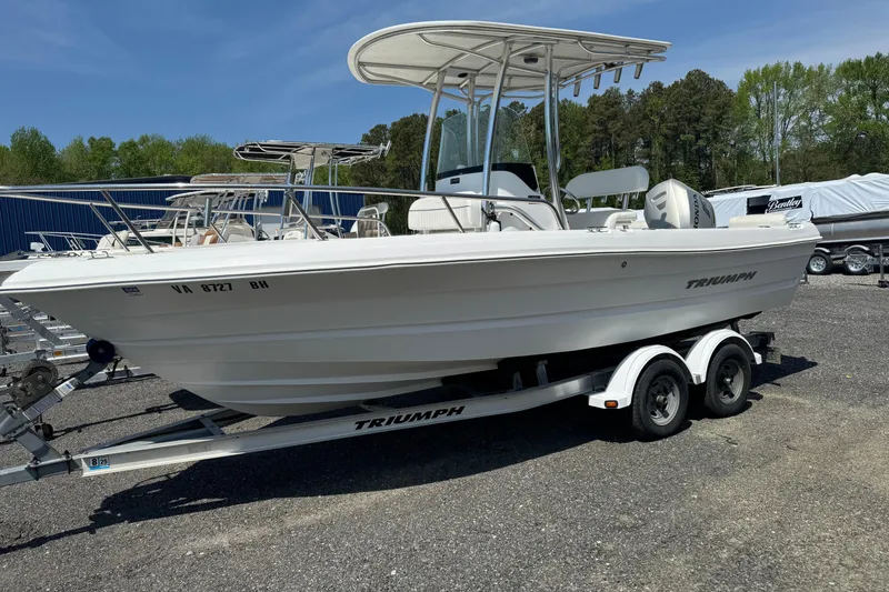 The Image of 2007 Triumph 215 TE boat on trailer, parked outdoors, featuring a sleek white design. - 0