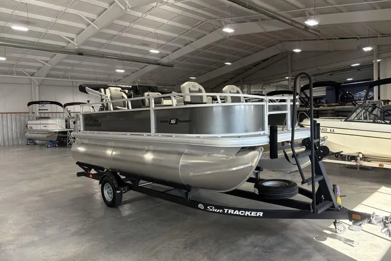 Slide: The Image of 2026 Sun Tracker Bass Buggy 16 XL Select pontoon boat in a showroom on a trailer. - 3