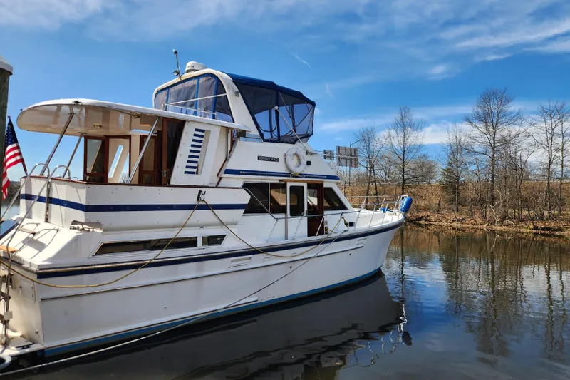 Slide: The Image of 1987 Jefferson 42 SE Sundeck Motor Yacht docked on a calm river under blue skies. - 2