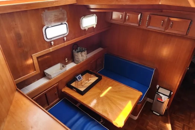 Slide: The Image of Cozy dining area in 1987 Jefferson 42 SE Sundeck Motor Yacht with blue seating and wooden table. - 24