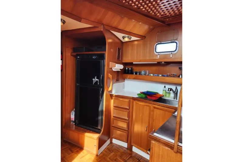 Slide: The Image of 1987 Jefferson 42 SE Sundeck Motor Yacht kitchen with wooden cabinetry and compact appliances. - 27