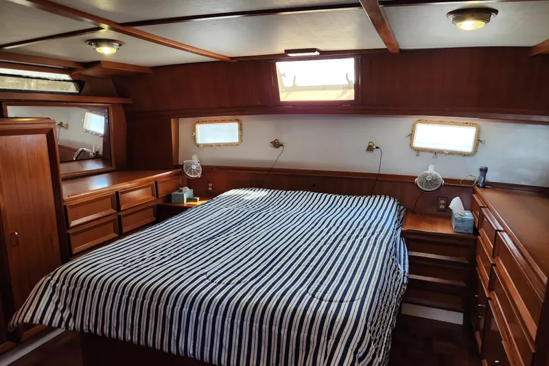 Slide: The Image of Luxurious 1987 Jefferson 42 SE Sundeck Motor Yacht bedroom with striped bedding and wooden cabinetry. - 29