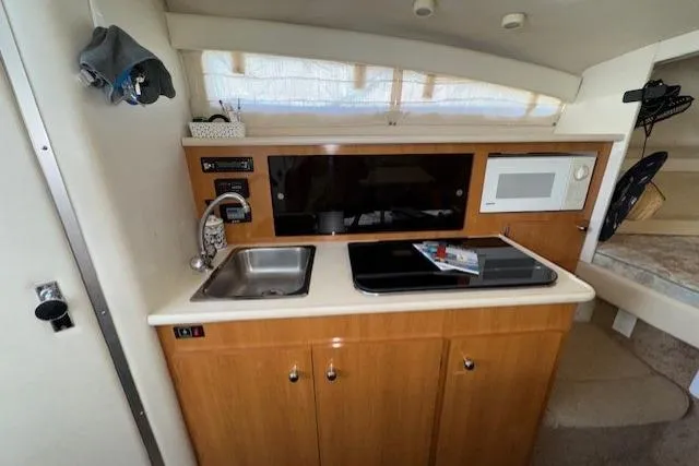 Slide: The Image of 2001 Bayliner 2855 Ciera boat interior kitchen with sink, stove, and microwave. - 7