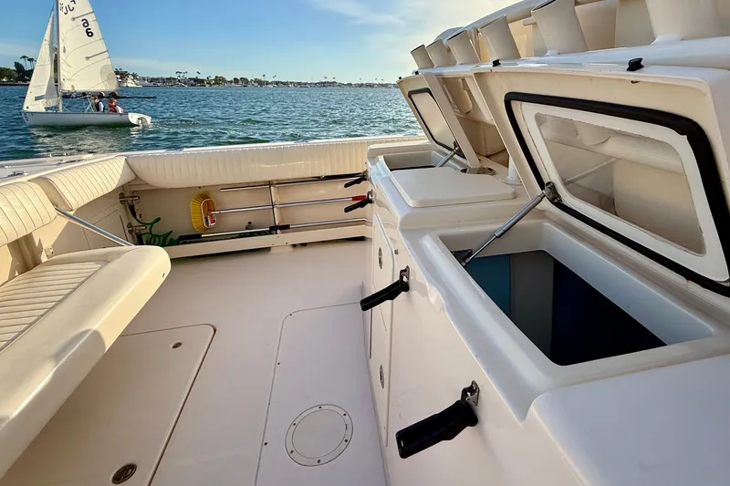 Slide: The Image of 2012 Grady-White Canyon 336 boat interior with open storage compartments, docked near sailboat. - 21