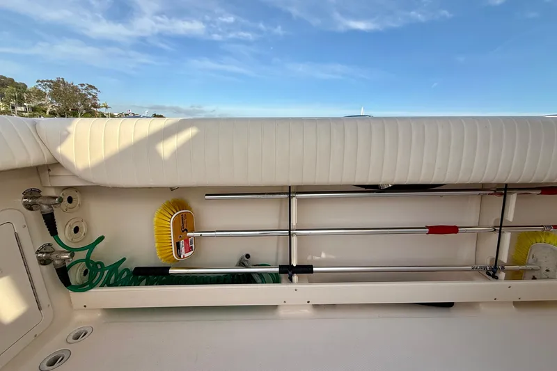 Slide: The Image of Storage compartment on a 2012 Grady-White Canyon 336 boat, featuring cleaning tools and hose. - 24