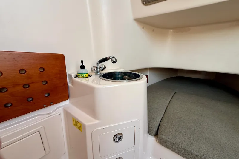 Slide: The Image of 2012 Grady-White Canyon 336 cabin interior with sink and cushioned seating area. - 49