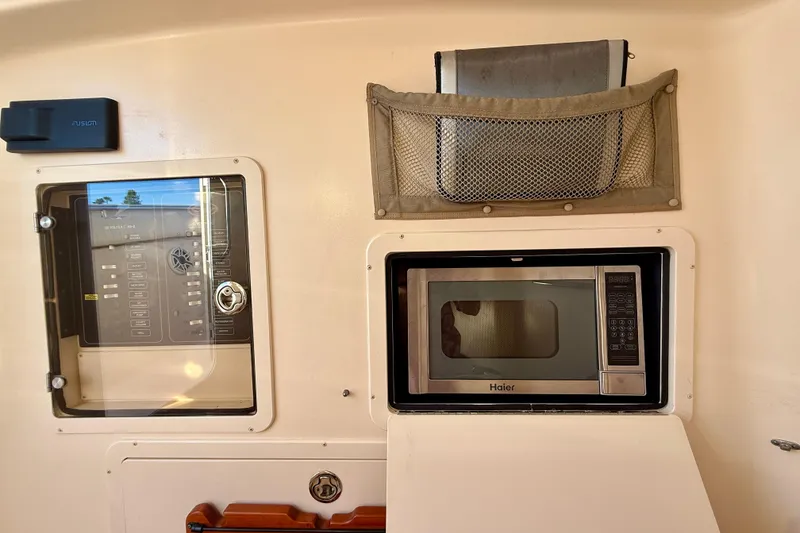 Slide: The Image of Interior of 2012 Grady-White Canyon 336 featuring a Haier microwave and control panel. - 54