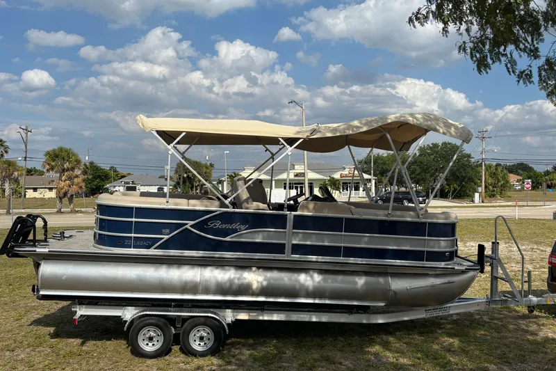 Slide: The Image of 2026 Bentley Pontoons Legacy 223 Navigator on trailer, blue hull, beige canopy. - 8