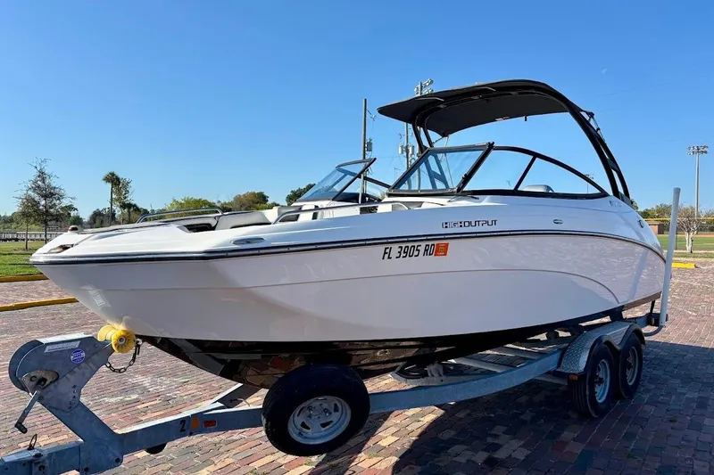 The Image of 2016 Yamaha Boats AR240 HO on trailer, parked outdoors under clear blue sky. - 1