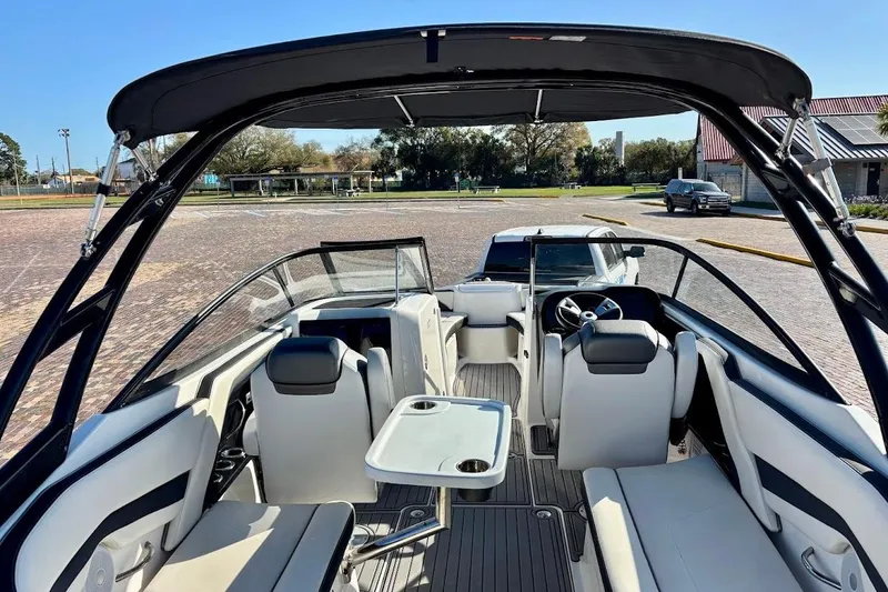 Slide: The Image of 2016 Yamaha Boats AR240 HO interior with seating and steering wheel, parked outdoors. - 13