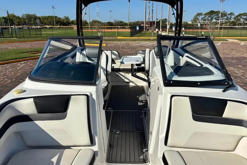 Slide: The Image of 2016 Yamaha Boats AR240 HO interior with seating and windshield, parked outdoors. - 14