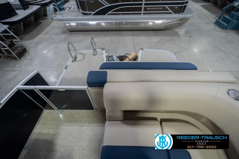 Slide: The Image of 2026 Bennington 21 SLJ pontoon boat interior with beige and blue seating, docked indoors. - 14