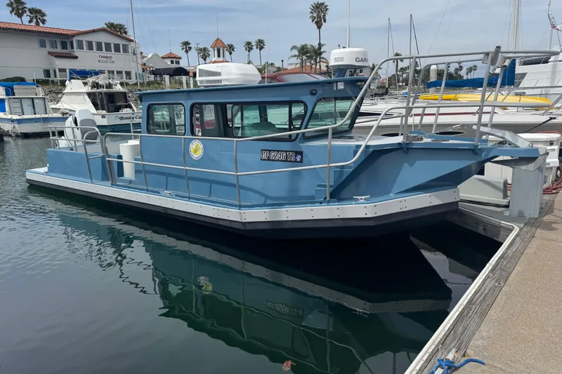 The Image of Blue ACB 30 boat docked in marina, 2003 model, with waterfront buildings in background. - 1