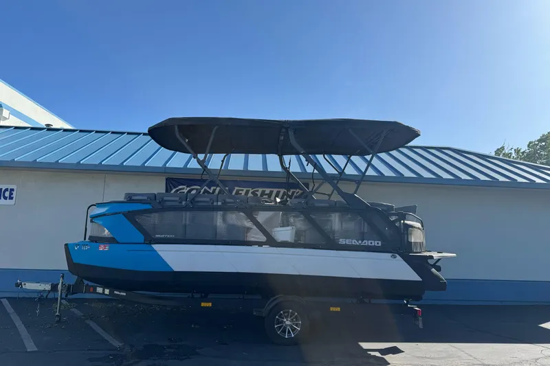 The Image of 2023 Sea-Doo Switch Cruise 21 pontoon boat with canopy, parked outside a building. - 0