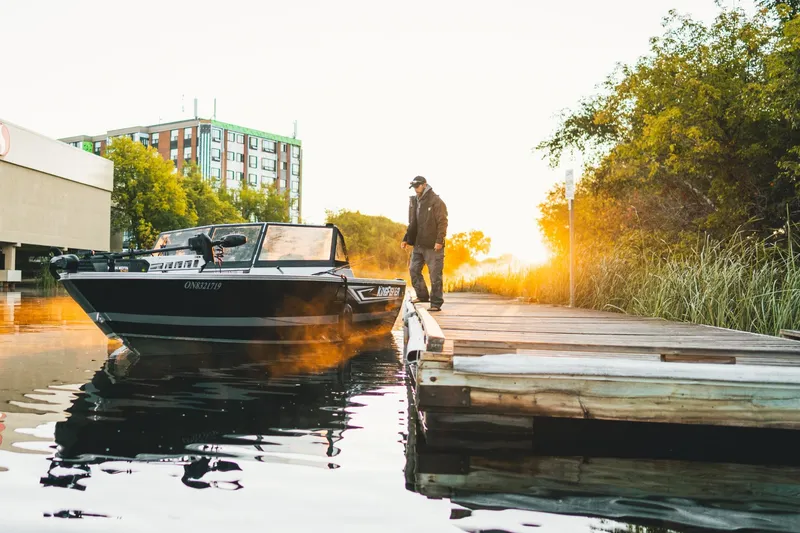 Slide: The Image of 2026 KingFisher 2125 Arrow Sport boat docked at sunset with a person standing nearby. - 11