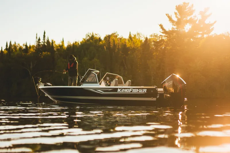 Slide: The Image of 2026 KingFisher 2125 Arrow Sport boat on serene lake at sunset, person fishing. - 12