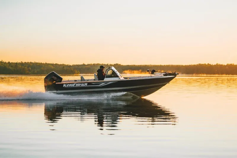 Slide: The Image of 2026 KingFisher 2125 Arrow Sport boat cruising on a serene lake at sunset. - 15