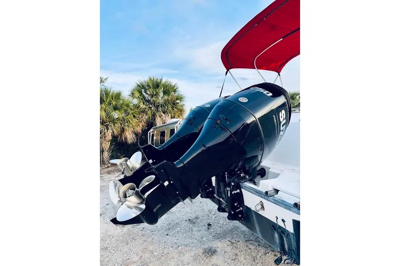 Slide: The Image of Outboard motor on a 2002 Boston Whaler 290 Outrage with red canopy, parked on sandy terrain. - 11