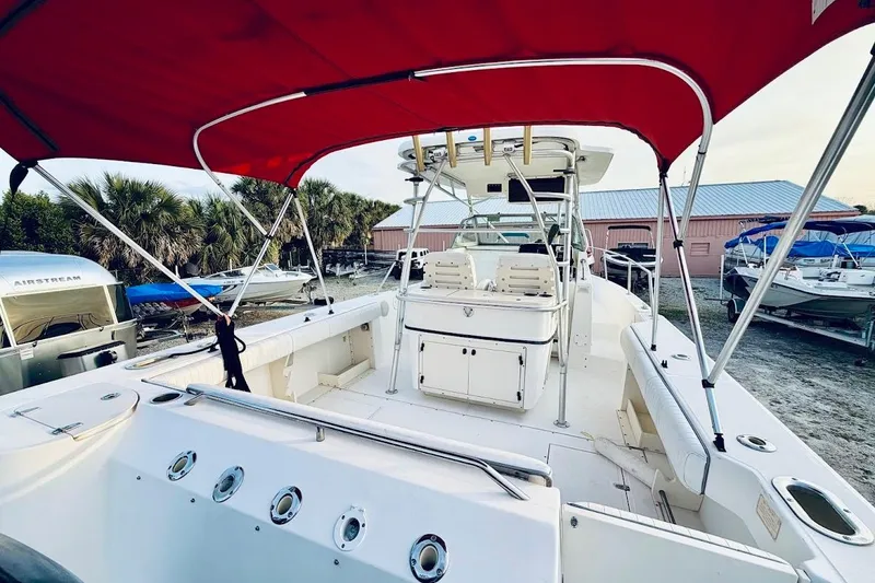 Slide: The Image of 2002 Boston Whaler 290 Outrage boat with red canopy, docked near palm trees. - 20