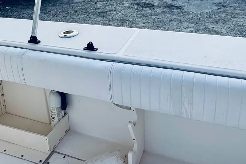 Slide: The Image of 2002 Boston Whaler 290 Outrage boat interior with white cushioned seating and storage compartment. - 22