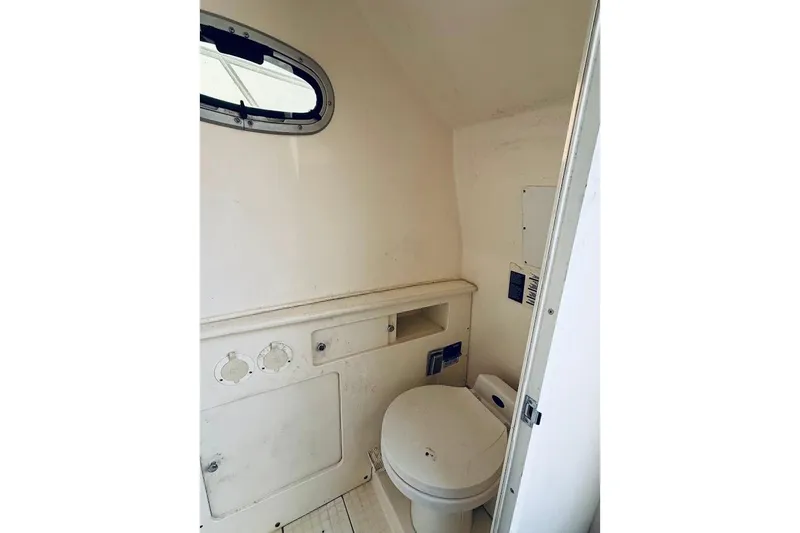 Slide: The Image of Interior of a 2002 Boston Whaler 290 Outrage boat bathroom with toilet and porthole. - 40